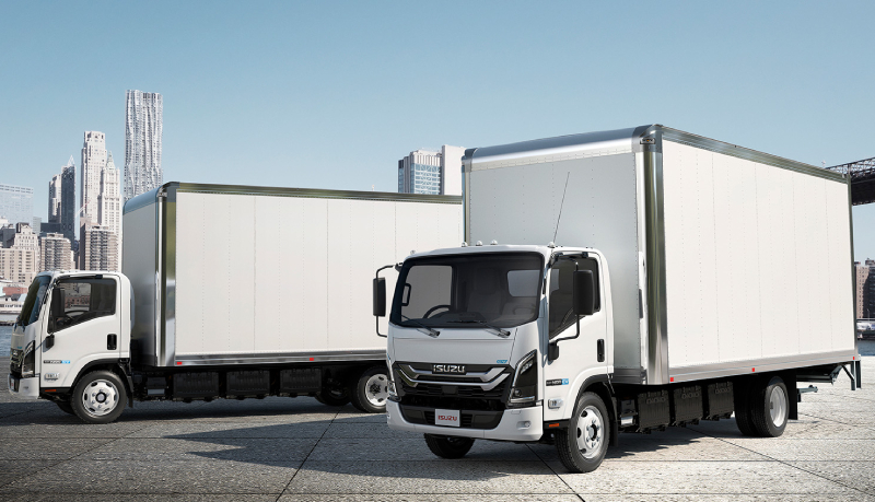 White isuzu truck driving down a road.